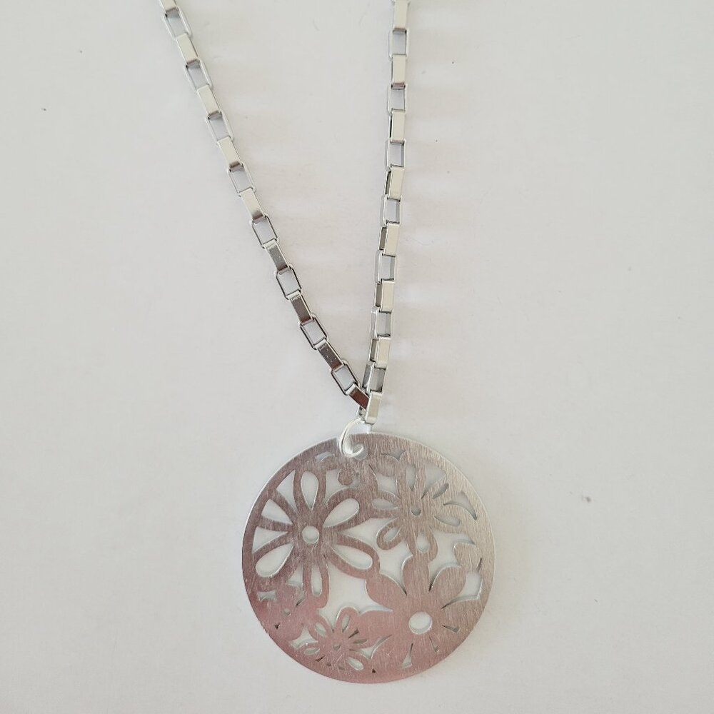 Collar plateado con dije circular de flores caladas